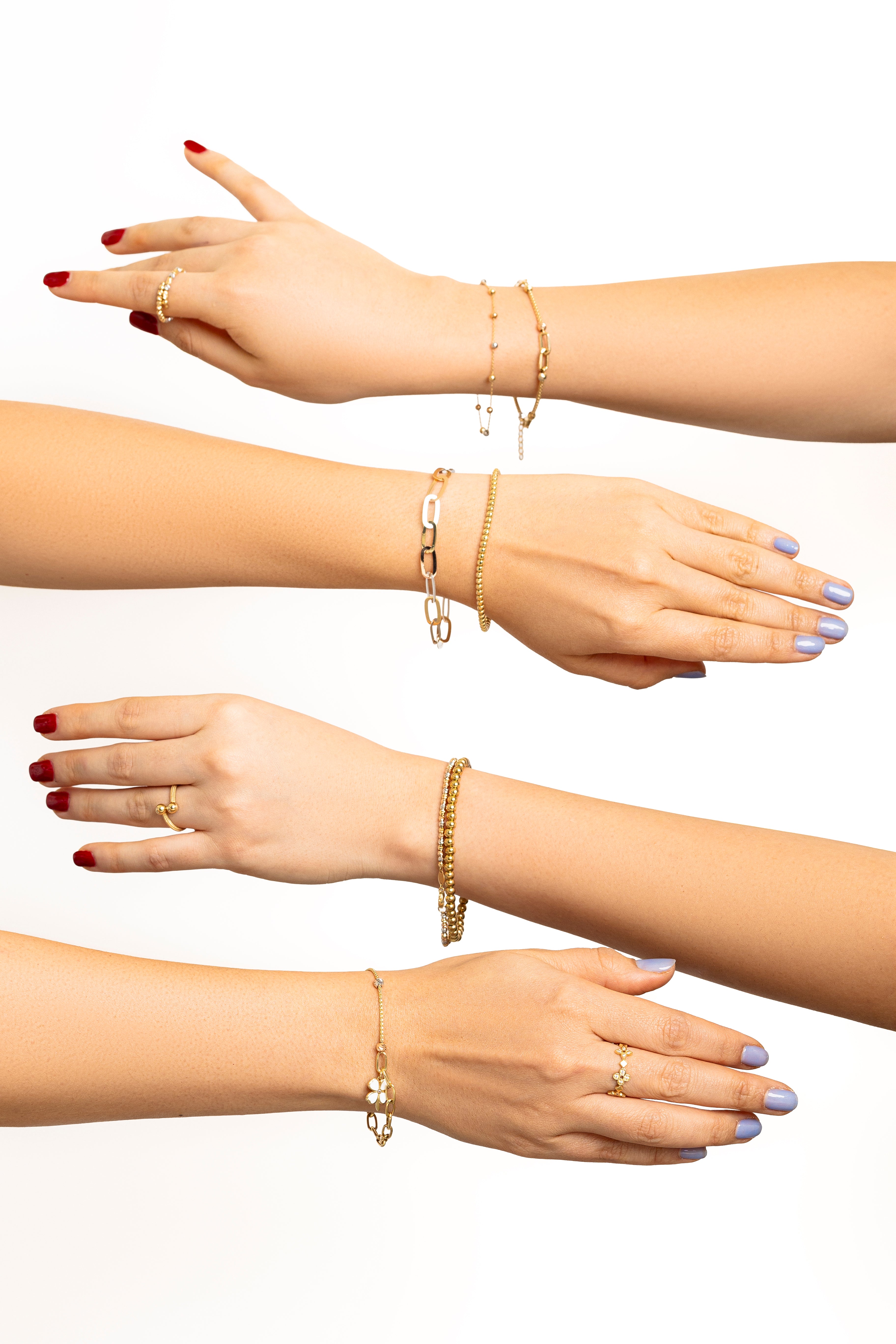 Cuatro manos mostrando diferentes pulseras y anillos de oro sobre fondo blanco.
