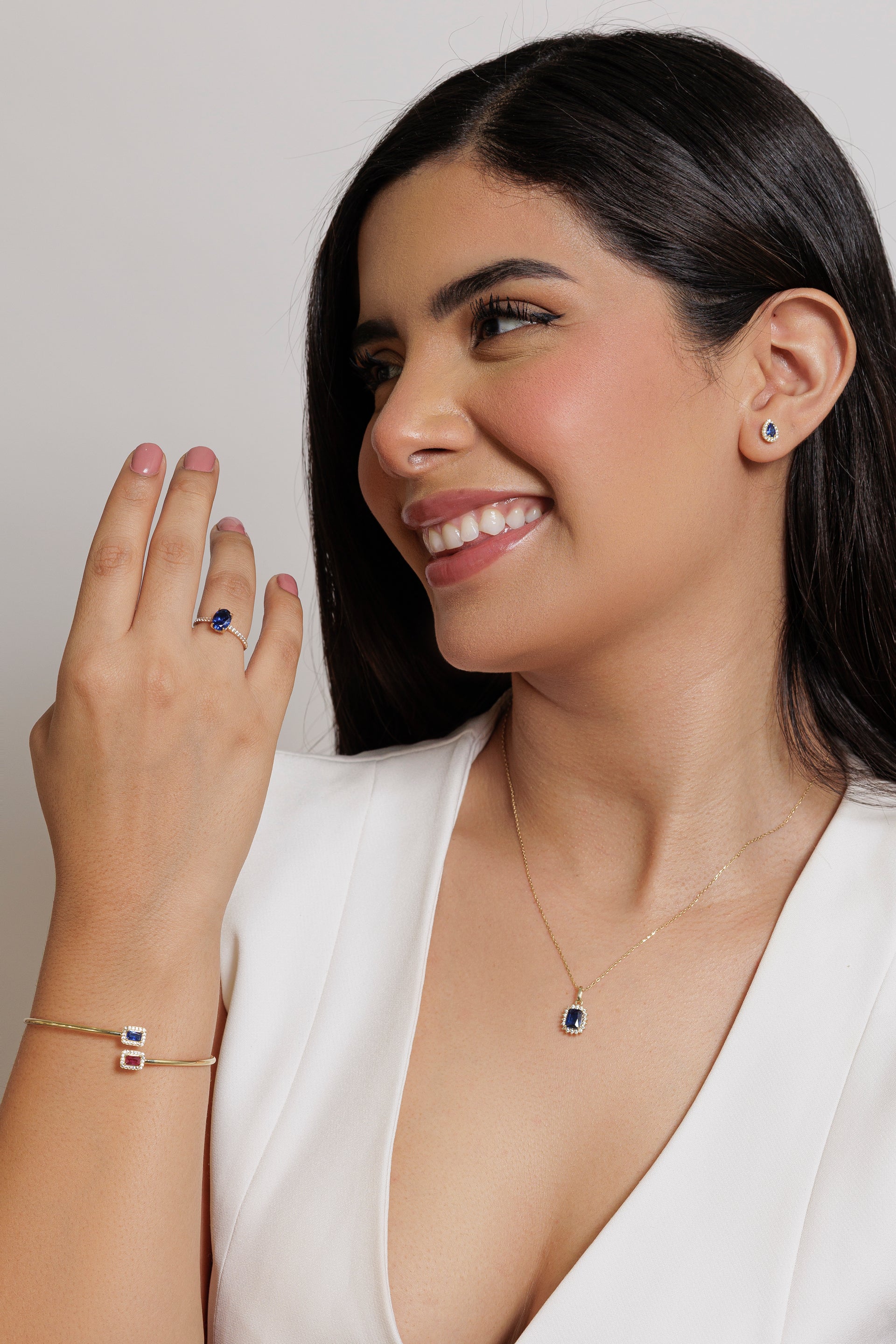 Mujer luciendo pulsera de oro con gemas de colores, combinada con anillo y collar.